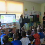 Dzieci uczestniczą w spotkaniu o segregacji śmieci prowadzonym przez przedstawicieli firmy zajmującej się recyklingiem.