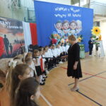 Pasowanie pierwszoklasistów na uczniów szkoły podczas uroczystości rozpoczęcia roku w sali gimnastycznej.