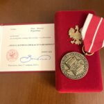 Medal Komisji Edukacji Narodowej w czerwonym etui wraz z legitymacją potwierdzającą przyznanie odznaczenia.