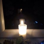 Zapalona świeca w oknie nocą – symbol pamięci o ofiarach stanu wojennego.