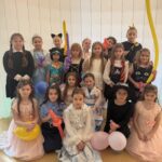 Grupa uczniów klas I–III w przebraniach karnawałowych pozuje do wspólnego zdjęcia w sali szkolnej podczas zabawy karnawałowej.