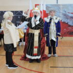 Dzieci przebrane w historyczne stroje odgrywają scenkę teatralną podczas szkolnego przedstawienia o tematyce narodowej