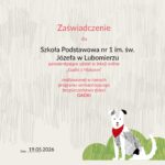 Zaświadczenie Fundacji Dajemy Dzieciom Siłę dla Szkoły Podstawowej nr 1 im. św. Józefa w Lubomierzu potwierdzające udział w lekcji online „Gadki z Maksem” realizowanej w ramach programu wzmacniającego bezpieczeństwo dzieci GADKI. Na jasnym tle widoczne kolorowe logo „GADKI”, czerwony tytuł „Zaświadczenie”, data 19.05.2026 oraz podpisy przedstawicielek fundacji. W prawym dolnym rogu znajduje się ilustracja biało-szarego psa w czerwonej chuście siedzącego na zielonej trawie.