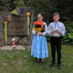 Uczennica i uczeń składają kwiaty dla upamiętnienia Jana Pawła II.