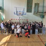 Zdjęcie grupowe uczniów klas I–VIII oraz prowadzących zajęcia z pierwszej pomocy w sali gimnastycznej. Uczestnicy pozują wspólnie po zakończeniu warsztatów realizowanych w ramach projektu „Ratuję, bo umiem”.