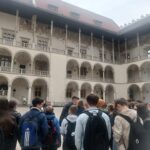Grupa uczniów znajdująca się na wewnętrznym arkadowym dziedzińcu Zamku Królewskiego na Wawelu