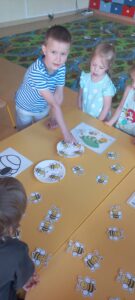 Chłopiec liczy pszczółki leżące na papierowych talerzykach.