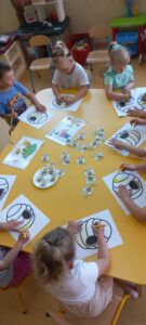 dzieci przyklejają pszczółki leżące na stole