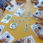 dzieci przyklejają pszczółki leżące na stole