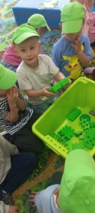 Dzieci wyciągają z pudełka rzeczy w zielonym kolorze.