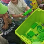 Dzieci wyciągają z pudełka rzeczy w zielonym kolorze.