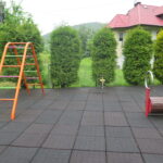 Fragment placu zabaw z widokiem na drabinkę łukową, urządzenie sprężynowe oraz przyrząd do ćwiczeń równowagi.