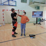 Ratownik demonstruje na uczniu, jak należy zabandażować ranę, aby zatamować rozległy krwotok