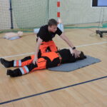 Ratownik demontruje na ratowniczce, jak należy ułożyć poszkodowanego w pozycji bocznej ustalonej