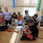 Ratownik wyjaśnia uczniom, jak należy postąpić w przypadku zatrzymania akcji serca u małego dziecka. Demontuje to na fantomie