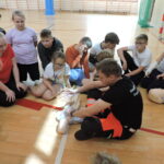 Ratownik wyjaśnia uczniom, jak należy wykonać resuscytację w przypadku zatrzymania akcji serca u małego dziecka. Demontuje to na fantomie