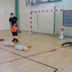 Ratownik wyjasnia uczniom, w jaki sposób sprawdza się, czy poszkodowany jest przytomny