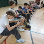 Uczniowie oglądają opaski uciskowe i zakładają je na ręce.