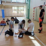 Uczniowie podzieleni na małe grupy, odgrywają scenki sytuacyjne, w których muszą wykonać resuscytację na fantomie i podłączyć AED