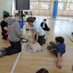 Uczniowie podzieleni na małe grupy, odgrywają scenki sytuacyjne, w których muszą wykonać resuscytację na fantomie i podłączyć AED