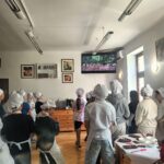 Uczniowie ubrani w czarpki i fartuchy ochronne oglądają film o hodowli kakaowców