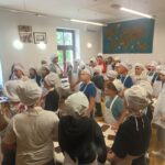 Uczniowie ubrani w czarpki i fartuchy ochronne słuchają wykładu o historii powstania czekolady