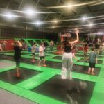 Uczniowie ubrani w sportowe stroje rozgrzewają się na trampolinach przed zabawami w GOjumpie