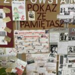 Fragment wystawy szkolnej: duży napis „Pokaż, że pamiętasz” oraz plakaty tematyczne o Powstaniu Warszawskim, z rysunkami dzieci, zdjęciami sanitariuszek i notatkami o bohaterach powstania.