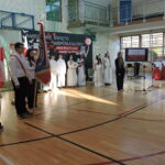 Poczet sztandarowy z flagą stoi przed sceną akademii z okazji Święta Niepodległości.