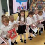 Dzieci dumnie prezentują swoje nowe książki i dyplomy czytelnika.