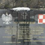 Kamienny pomnik pamięci z tablicą poświęconą ofiarom katastrofy smoleńskiej i zbrodni katyńskiej, na tle zimowego parku.