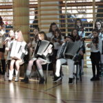 Uczniowie grają na instrumentach muzycznych podczas szkolnego występu świątecznego.