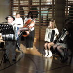 Uczniowie grają na instrumentach muzycznych podczas szkolnego występu świątecznego.