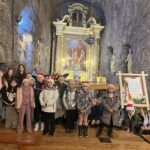 Dzieci stoją przed solnym ołtarzem w kaplicy podziemnej, otoczone rzeźbami i elementami ozdobnymi wykutymi w skale