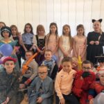 Grupa uczniów klas I–III w przebraniach karnawałowych pozuje do wspólnego zdjęcia w sali szkolnej podczas zabawy karnawałowej.