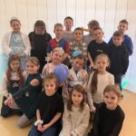 Grupa uczniów klas I–III w przebraniach karnawałowych pozuje do wspólnego zdjęcia w sali szkolnej podczas zabawy karnawałowej.