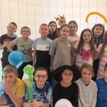 Grupa uczniów klas I–III w przebraniach karnawałowych pozuje do wspólnego zdjęcia w sali szkolnej podczas zabawy karnawałowej.