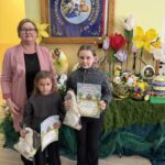 Laureatki konkursu z nagrodami i dyplomami na tle wystawy konkursowych pisanek i wiosennych dekoracji.