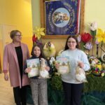 Laureatki konkursu z nagrodami i dyplomami na tle wystawy konkursowych pisanek i wiosennych dekoracji.