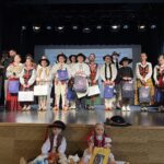 Uczniowie w strojach regionalnych stoją na scenie podczas gali konkursu „Góralskie Cytanie”, trzymając nagrody i dyplomy.