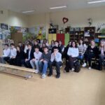 Uczniowie oraz nauczyciele siedzący na widowni podczas konkursu, skupieni i uważnie obserwujący wydarzenie.