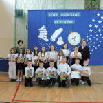 Pamiątkowe zdjęcie klasy III z wychowawcą i dyrektorem oraz nagrodami i dyplomami otrzymanymi na zakończenie roku szkolnego
